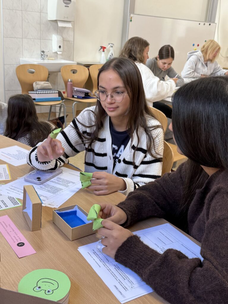 Schülerinnen basteln Papierfrösche in einem Klassenzimmer in Österreich